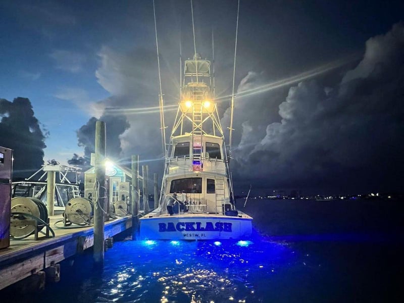 The back of Backlash at night at a dock in Destin, Florida