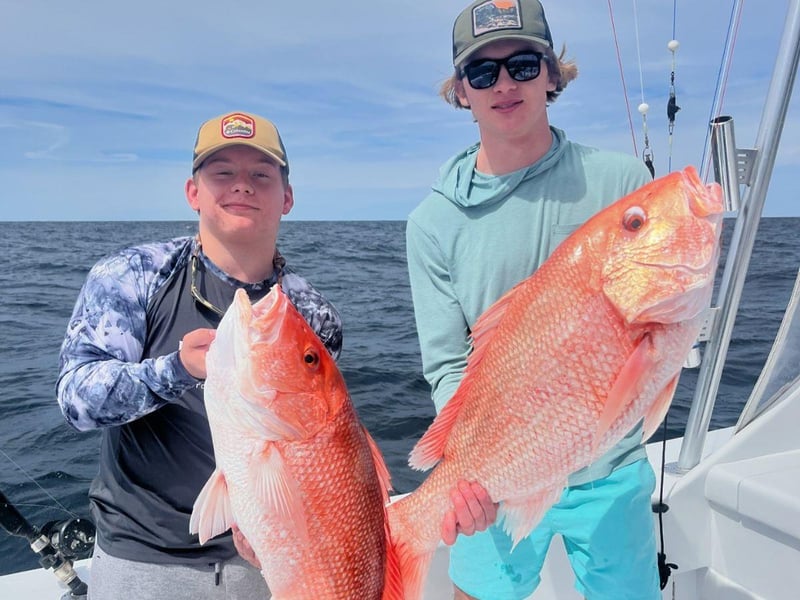 Two fishers holding Red Snapper aboard Backlash