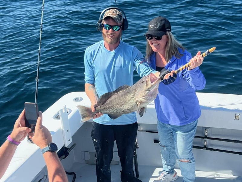 Two people holding a fishin on First Light off the coast of Destin, Florida