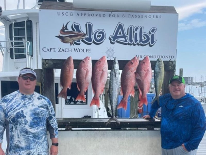A group showing off their catch from No Alibi on the dock