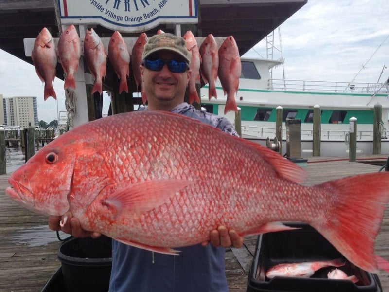 A man showing off his catch with Action Charter Service on the dock