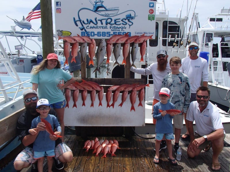 A family with their catch on the dock in front of the Huntress