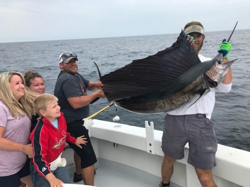 A man holding a sail fish aboard the Huntress in Destin, Florida