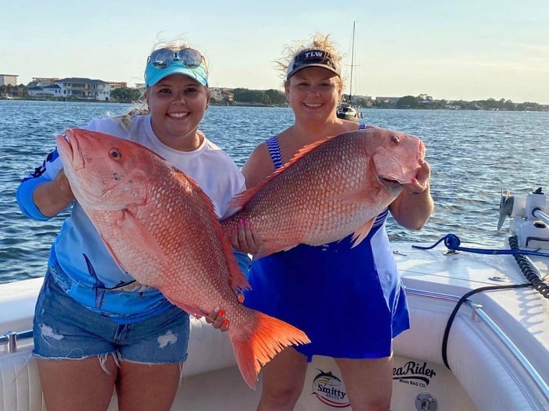 Two women holding lrage red snapper aboard JustInTime in Destin, Florida