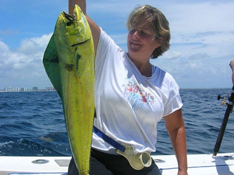 A woman holding a large Mahi Mahi on Lucky Lina in Destin, Florida