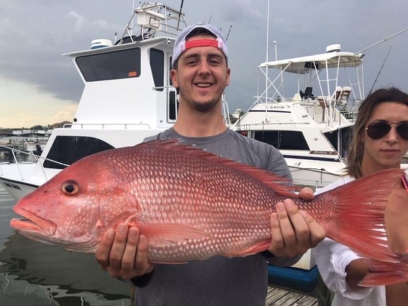 A man holding a large Red Snapper from a trip with Sure Shot Fishing Charters