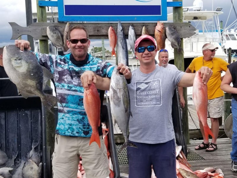 A group holding their catch on the dock in Oragne Beach, Alabama