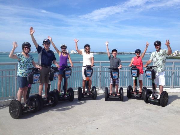 Posing on Segways rented from The Segway Adventure, 7 riders  wave at the camera.