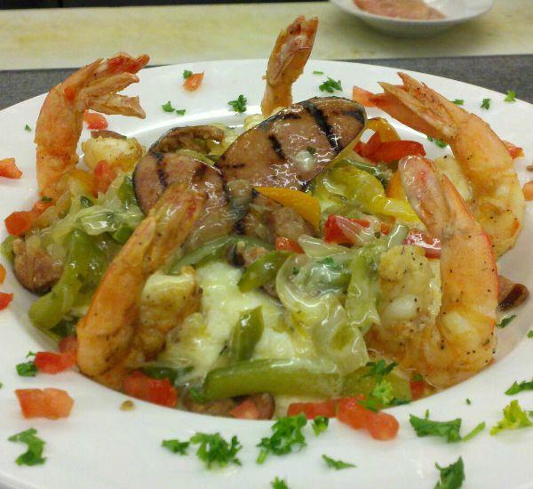 Jumbo shrimp and grilled fish plated with green beans, onions, peppers, and other fresh vegetables