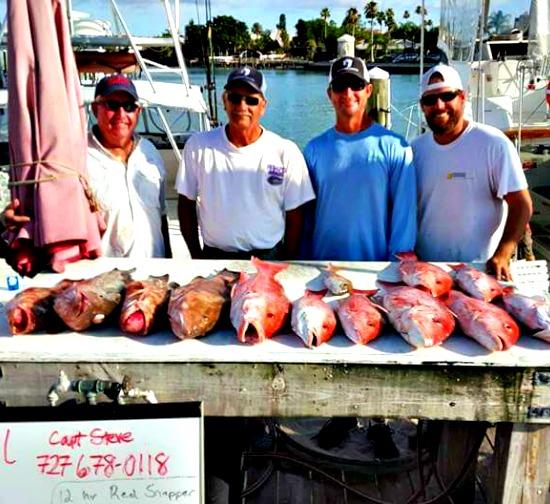 Four happy fishermen standing on the dock behind their catch after fishing with Reel Deal Sportfishing in Clearwater Beach, Florida