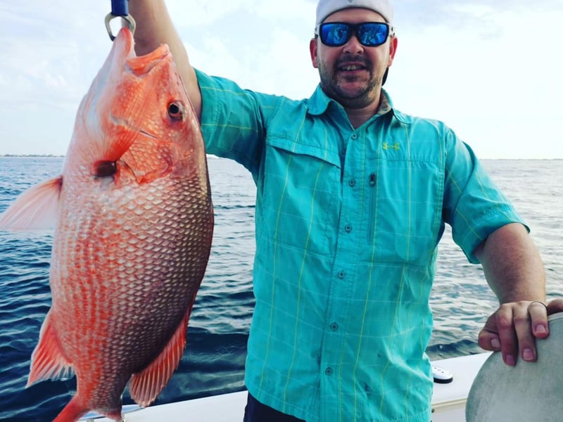 An angler with his fish off the coast of Pensacola Beach, Florida