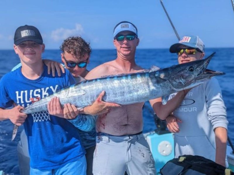 Four people holding their catch on board Get the Gaff charter off the coast of Destin, Florida