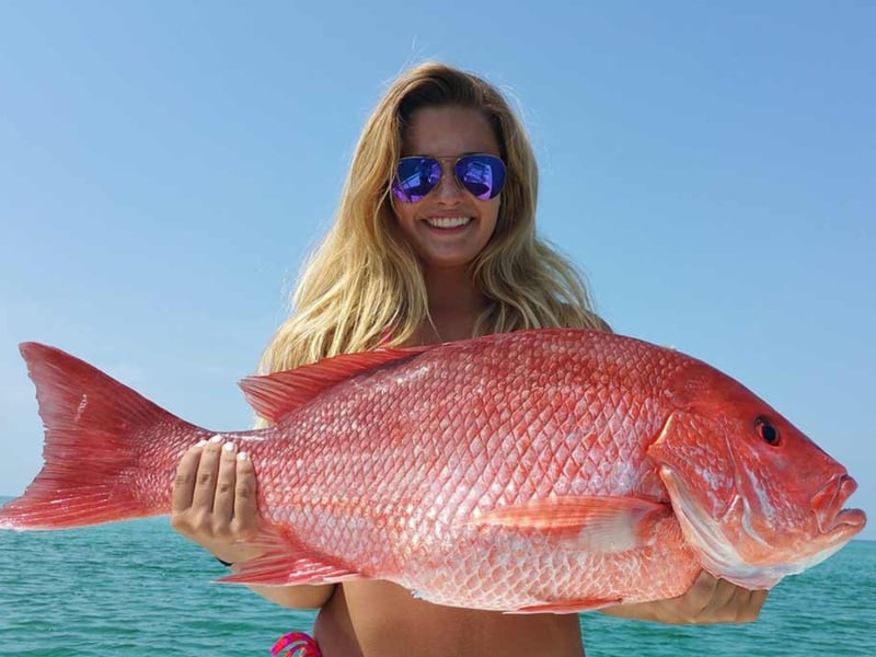 A women with a large snapper with Calibrated Fishing Charters
