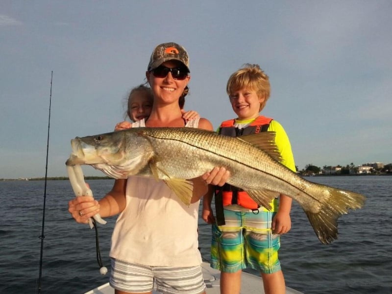 A family showing off their catch on the back of the Reel Knowledge Fishing boat