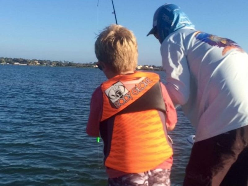 Two boys fishing off the side of a boat in Sarasota, Florida