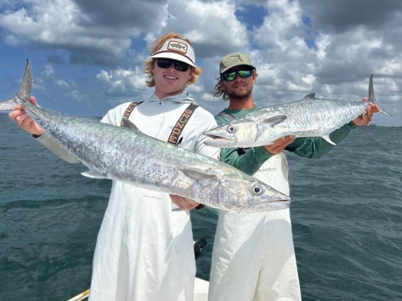 Two men showing off their catch with Windward Fishing Charters