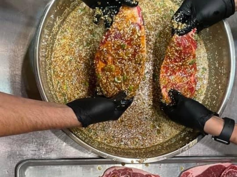 Two chefs seasoning pork at Bonellis in Pensacola, Florida