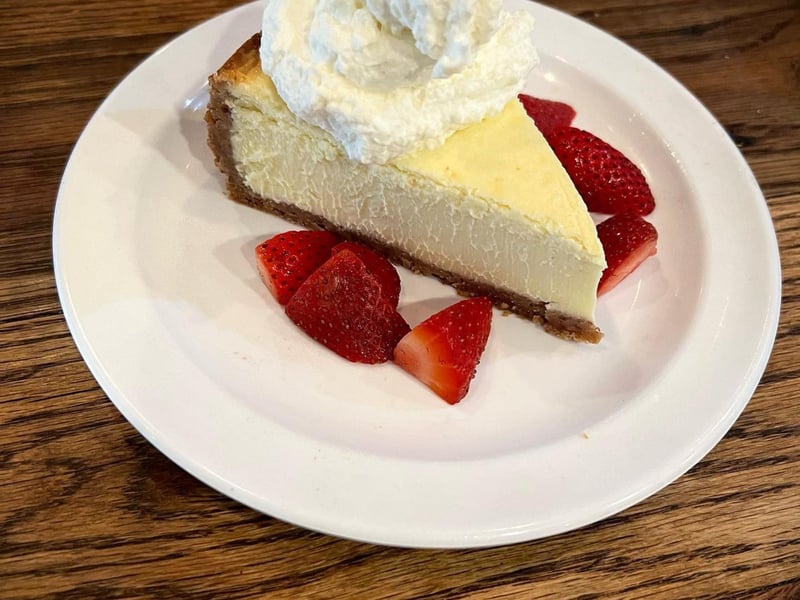 Roadhouse cheesecake with whipped cream and fresh strawberries