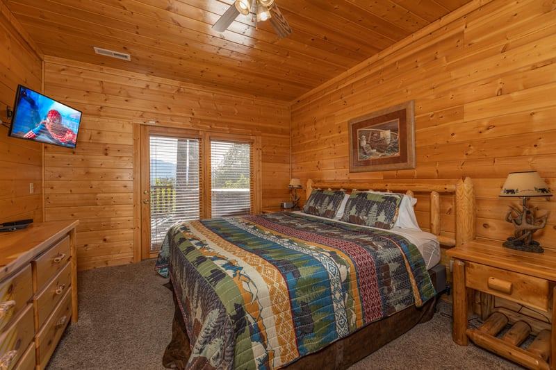 Bedroom with a dresser, TV, and deck access at Grizzlys Den, a 5 bedroom cabin rental located in Gatlinburg