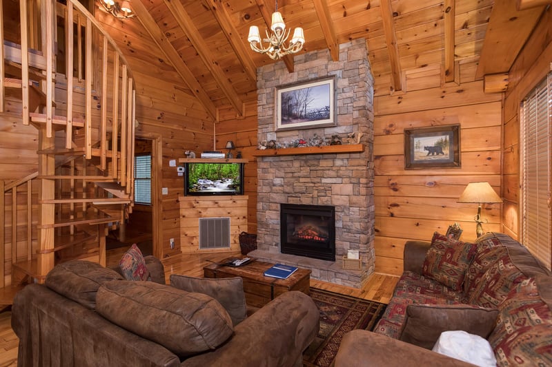 living room with a stone fireplace and spiral staircase at always  forever a 1 bedroom cabin rental located in pigeon forge