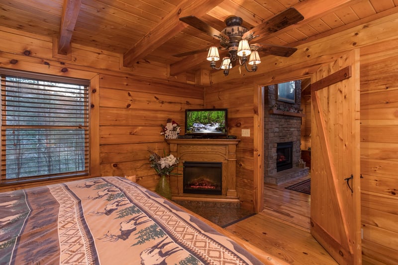 master bedroom with fireplace and television at always  forever a 1 bedroom cabin rental located in pigeon forge