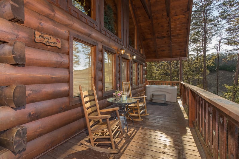 rocking chairs and hot tub on a covered deck at always  forever a 1 bedroom cabin rental located in pigeon forge