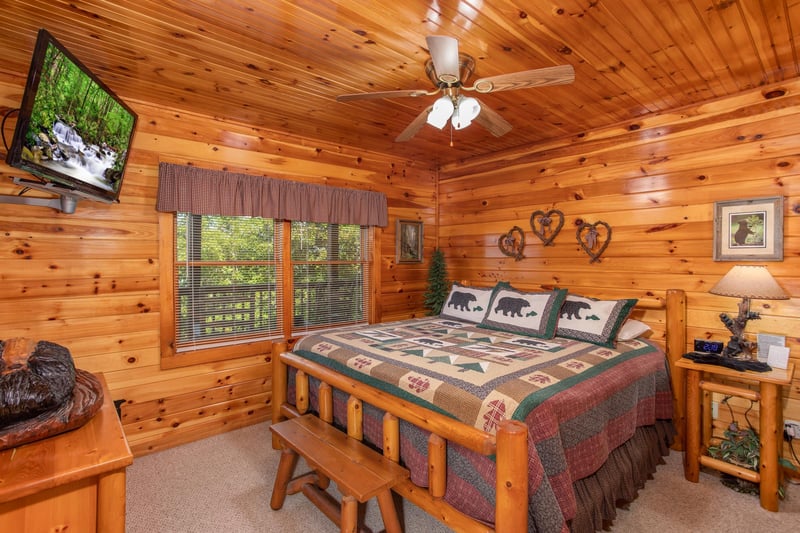 Kingsized log bed with flat screen television at Bear Country, a 3bedroom cabin rental located in Pigeon Forge