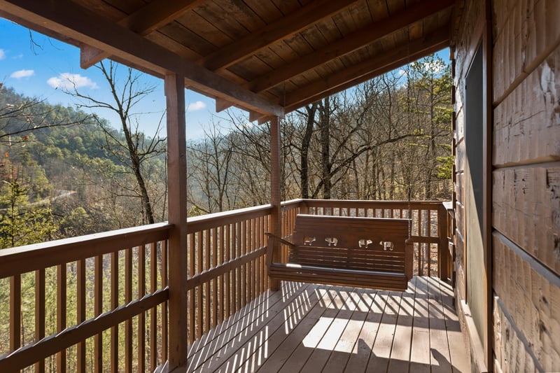 Swing on a covered deck at Mountain Magic, a 1 bedroom cabin rental located in Pigeon Forge