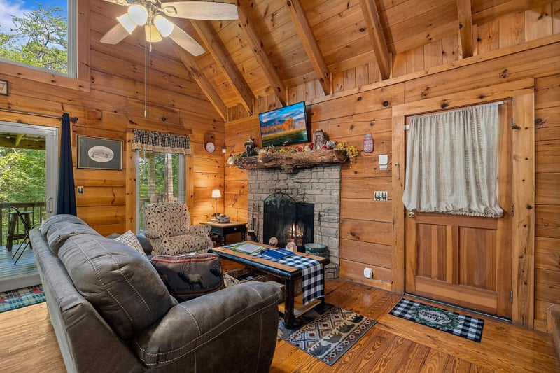 Living room with fireplace, tv, and deck access at Cloud 9, a 1bedroom cabin rental located in Pigeon Forge