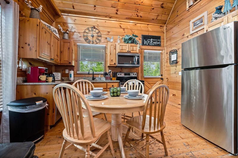 Dining table for four in a kitchen with stainless appliances at Honey Bear Haven, a 1 bedroom cabin rental located in Pigeon Forge