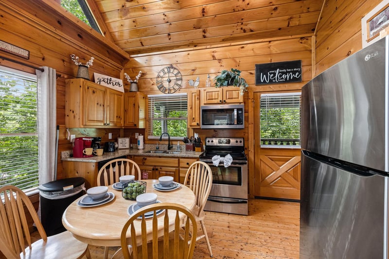 Dining table for four in a kitchen with stainless appliances at Honey Bear Haven, a 1 bedroom cabin rental located in Pigeon Forge