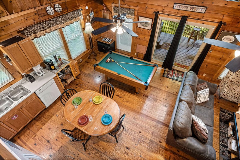 Living room, dining space, and pool table from the loft at Cloud 9, a 1bedroom cabin rental located in Pigeon Forge