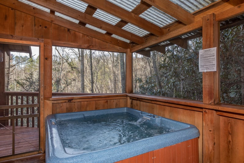 Hot tub on a covered deck at Moonshiners Ridge, a 1bedroom cabin rental located in Pigeon Forge