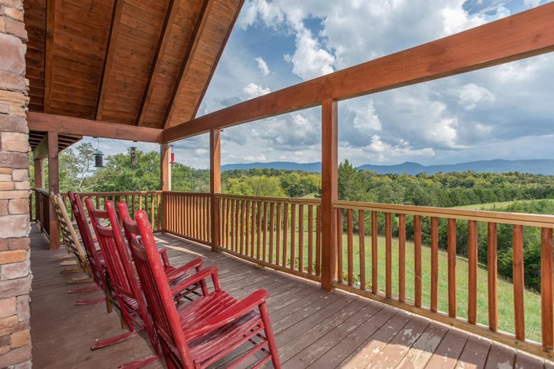 Rocking chairs lined up on a covered deck with lake and mountain views at Cedar Creeks, a 2bedroom cabin rental located near Douglas Lake