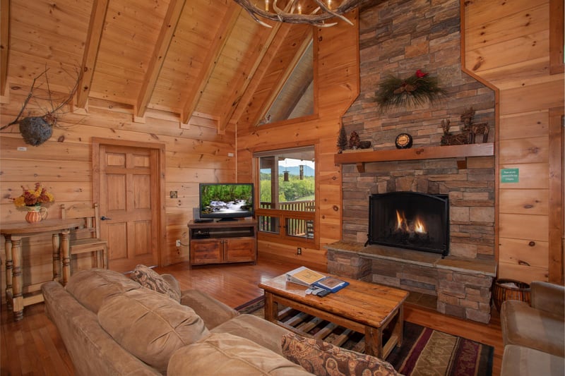 A vaulted living room with fireplace and television at Cedar Creeks, a 2bedroom cabin rental located near Douglas Lake