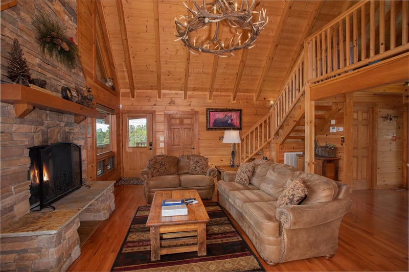 Couch, sofa, fireplace, and custom chandelier in the living room at Cedar Creeks, a 2bedroom cabin rental located near Douglas Lake