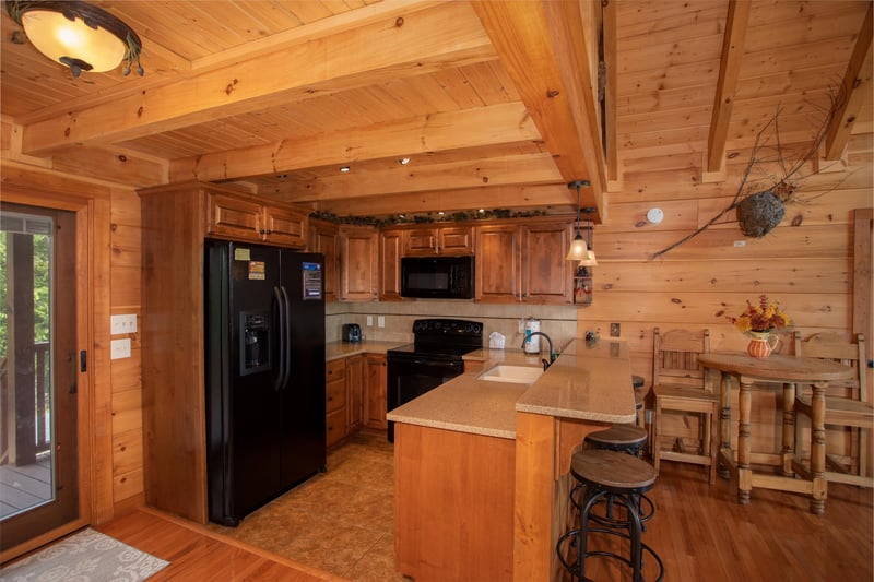 Kitchen with black appliances, counter top seating, and a high top dining table at Cedar Creeks, a 2bedroom cabin rental located near Douglas Lake