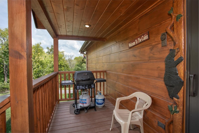 Propane grill on a covered deck with custom black bear decor at Cedar Creeks, a 2bedroom cabin rental located near Douglas Lake