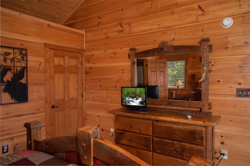 Bedroom with a dresser and mirror and a television at Cedar Creeks, a 2bedroom cabin rental located near Douglas Lake