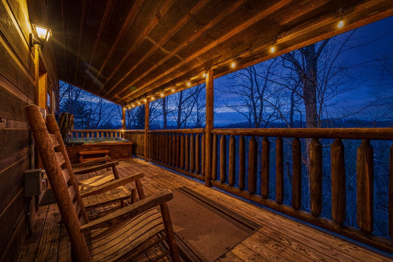 Rocking chairs and hot tub on a covered deck at Moonshine Memories, a 2 bedroom cabin rental located in Gatlinburg