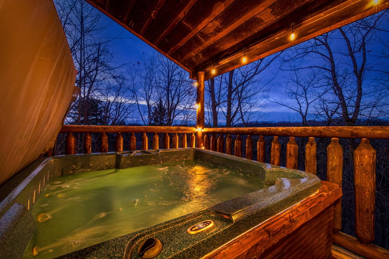 Hot tub at night on a covered deck at Moonshine Memories, a 2 bedroom cabin rental located in Gatlinburg