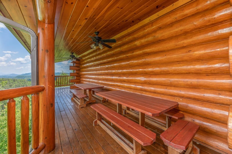 Picnic tables on a covered deck at Gods Country, a 4 bedroom cabin rental located in Pigeon Forge