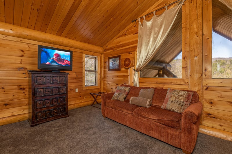 Sofa, dresser, and TV at Gods Country, a 4 bedroom cabin rental located in Pigeon Forge