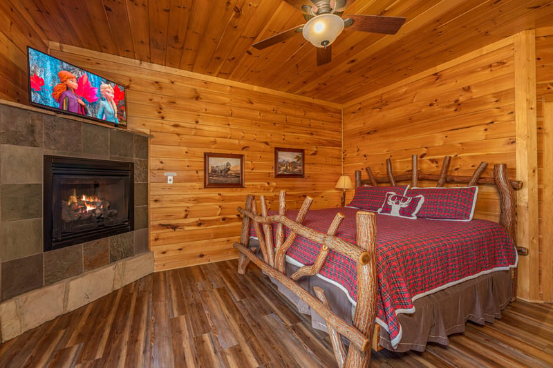 Bedroom with a king bed, fireplace, and TV at Gods Country, a 4 bedroom cabin rental located in Pigeon Forge