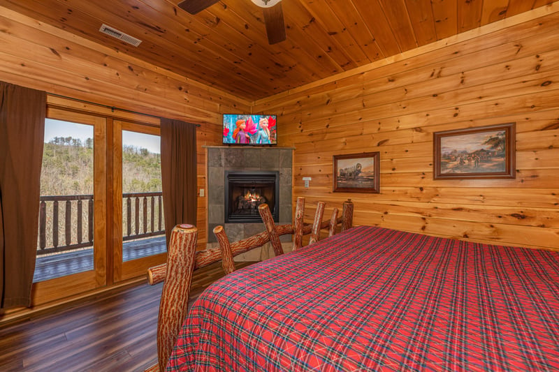 Fireplace, TV, and deck access in a bedroom at Gods Country, a 4 bedroom cabin rental located in Pigeon Forge