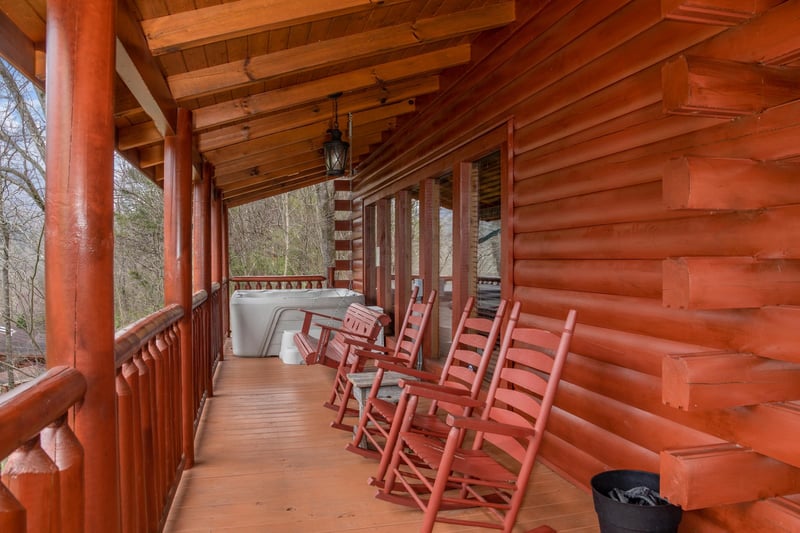 Rocking chairs and hot tub on a covered deck at Mountain View Meadows, a 3 bedroom cabin rental located in Pigeon Forge