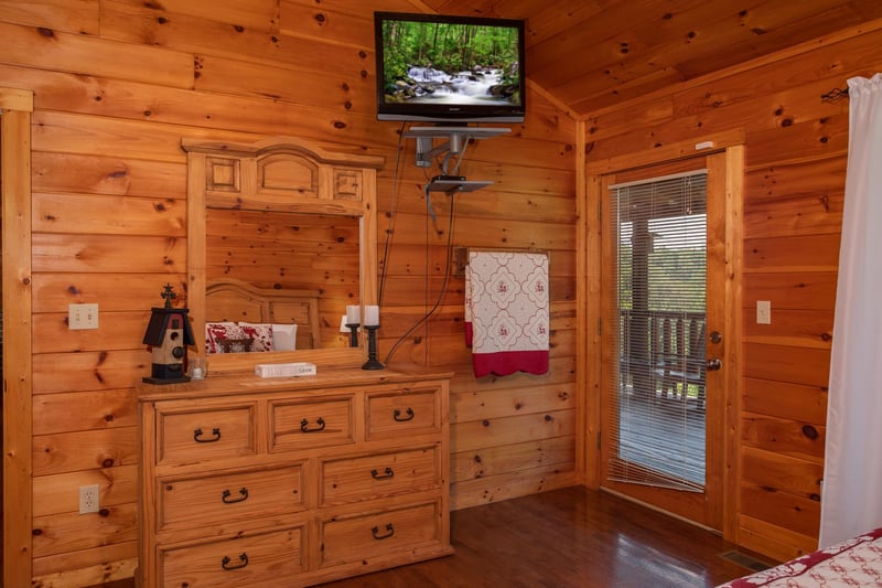 Bedroom with a dresser and mirror, a wallmounted television, and deck access at Cabin Fever, a 4bedroom cabin rental located in Pigeon Forge