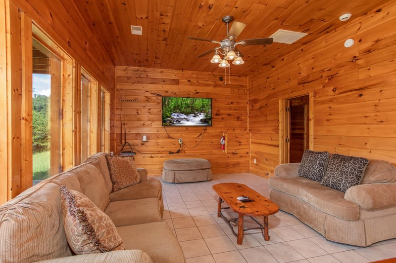 Television, couch, loveseat, and ottoman in the game room at Cabin Fever, a 4bedroom cabin rental located in Pigeon Forge