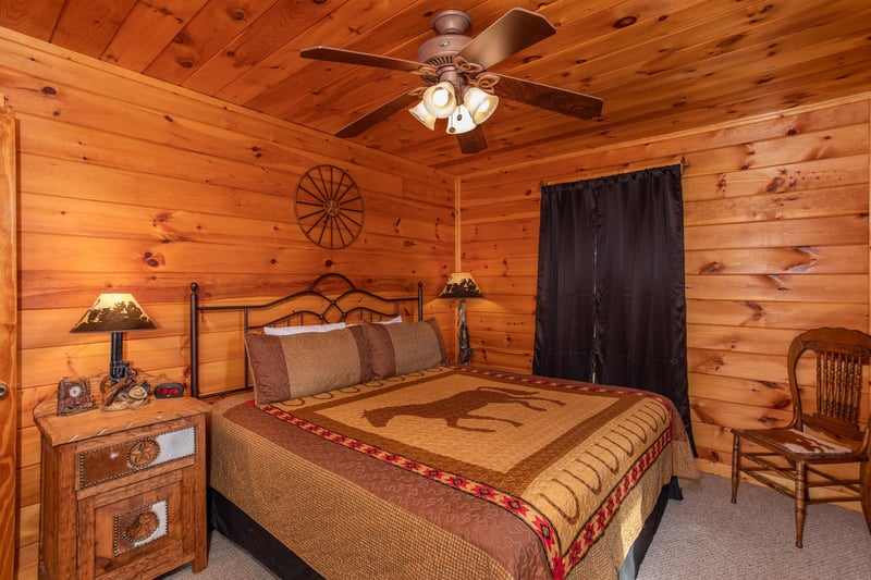 Bedroom with a kingsized bed, two end tables, and a chair at Cabin Fever, a 4bedroom cabin rental located in Pigeon Forge