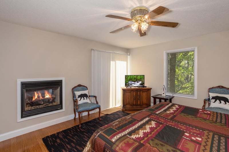 Bedroom with an inwall fireplace, sitting area, TV, and deck access at Into the Woods, a 3 bedroom cabin rental located in Pigeon Forge